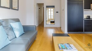 Un salon moderne avec un canapé gris, une table basse en bois et des œuvres d’art encadrées accrochées au mur.
