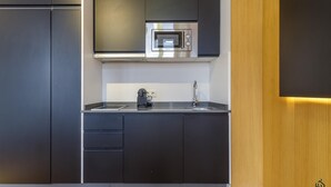 Une cuisine moderne avec des meubles de couleur sombre, un four en acier inoxydable et un évier.