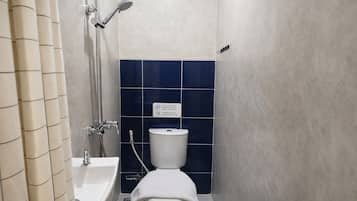 A small, compact bathroom with a toilet, a shower, and a bathtub.