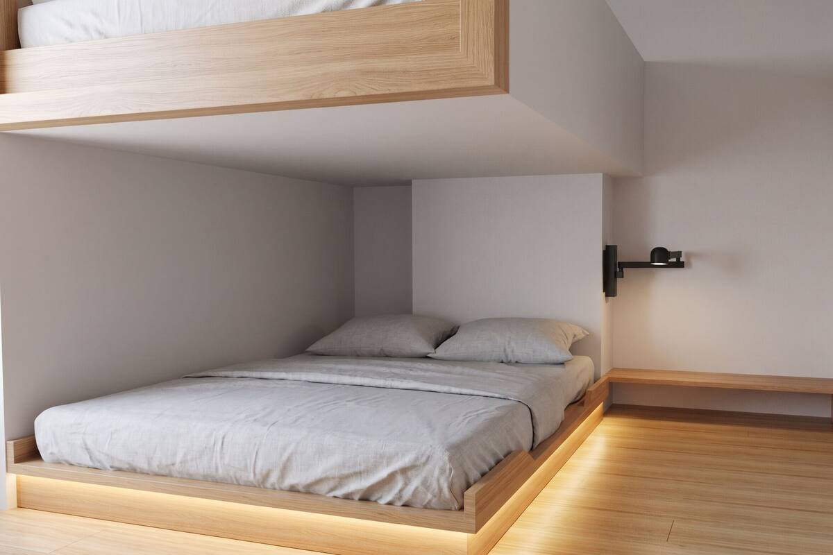 A minimalist bedroom with a bed, a wall-mounted light, and a wooden platform.