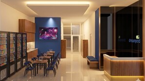 A modern hotel lobby with a reception desk, seating area, and a wall-mounted TV. - Dreampod Soekarno Hatta Airport (Tangerang)
