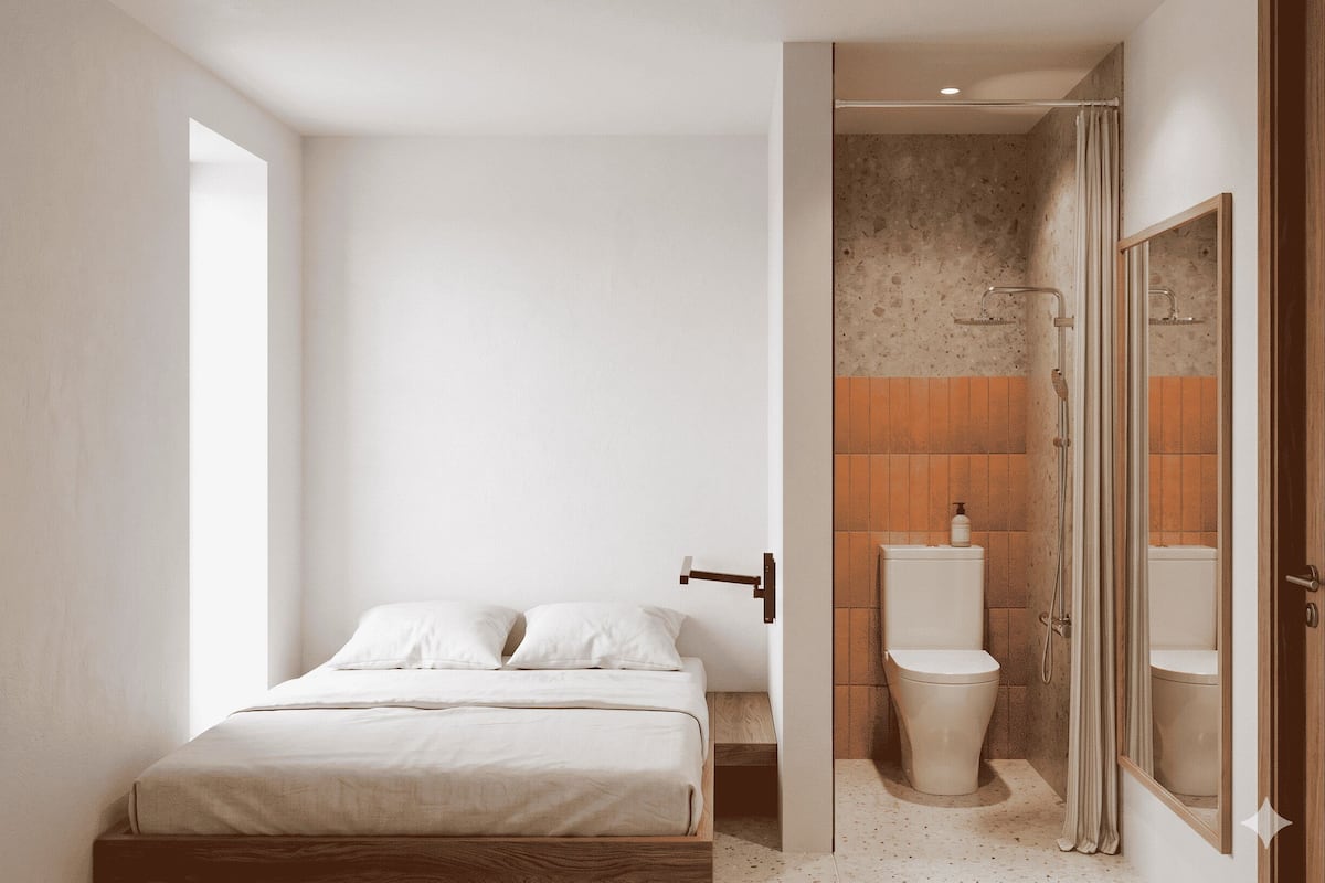 A bedroom with a bed, a bathroom with a toilet and shower, and a door leading to another room.