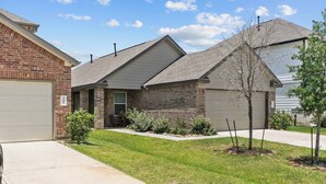 A residential house with a brick facade, a front garage, and a well-maintained lawn. - Convenient Family Home in Heart of Conroe (Conroe)