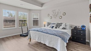 A bedroom with a bed, a dresser, and a window with blinds. - Convenient Family Home in Heart of Conroe (Conroe)