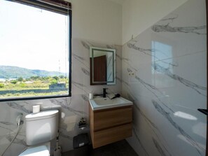 A bathroom with a toilet, sink, and mirror. - Mar Bella Beachfront Hotel (Kuta)