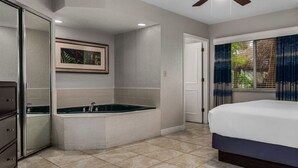 Un dormitorio con una cama grande, un vestidor, una bañera y un ventanal con cortinas.