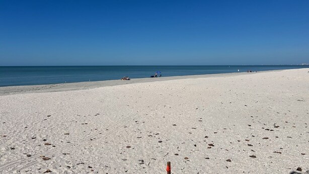 A wide sandy beach with a clear blue sky and calm sea. - Getaway beach house, Downstairs unit (Fort Myers Beach)