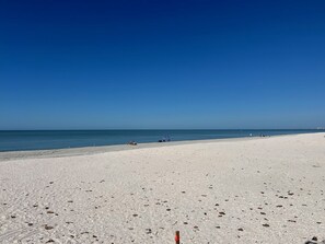 Una extensa playa arenosa con cielo azul despejado y mar tranquilo.