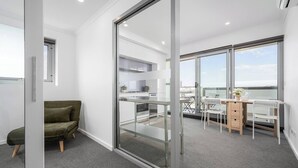 En moderne lejlighed med balkon, køkken og spiseplads med bord og stole.