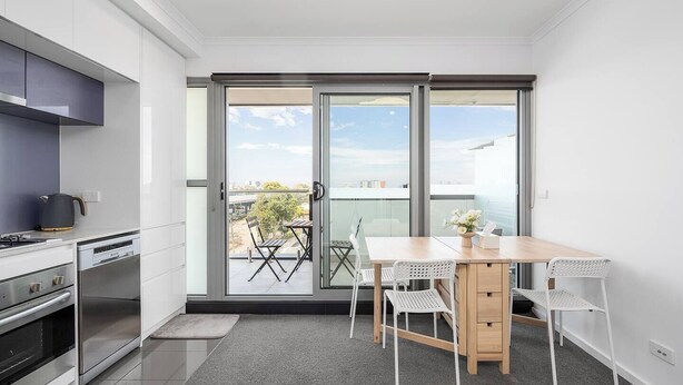 Et moderne køkken med spiseplads, en skydedør til en balkon og udsigt over bybilledet.