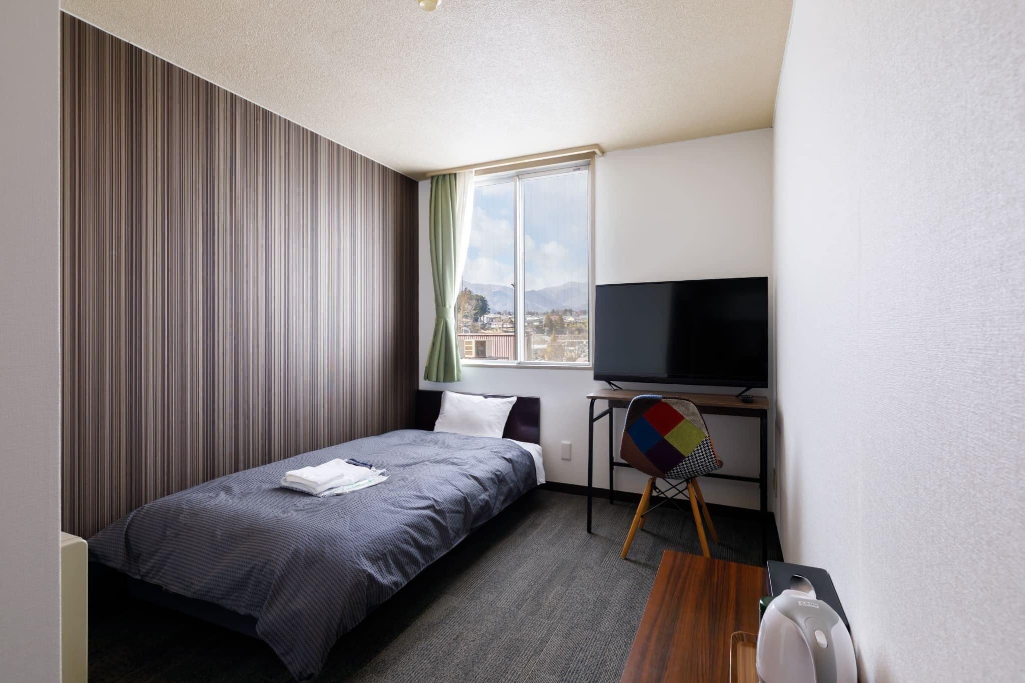 Una habitación de hotel con una cama, televisión, escritorio y una silla.
