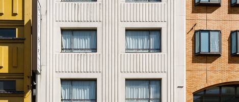 Un edificio moderno con fachada plana, múltiples ventanas y una entrada visible.