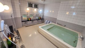A modern bathroom with a large bathtub, multiple sinks, and a shower area.