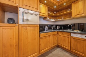 A kitchen with wooden cabinets, a Bosch dishwasher, and a stainless steel oven. - V Balme 12: Beside Ski Lift; Pool, Sauna & Gym, Vallorcine (Argentiere), France (Vallorcine (Argentiere))
