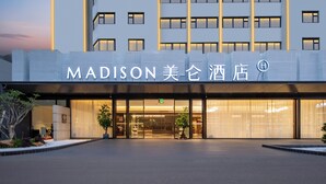 Ein moderner Hotelzugang mit einem großen Schild, auf dem “MADISON 美伦酒店” steht.