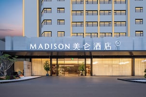 Una entrada de hotel moderna con un gran letrero que dice "MADISON 美伦酒店".