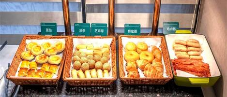 A buffet with labeled baskets of various pastries and meats.