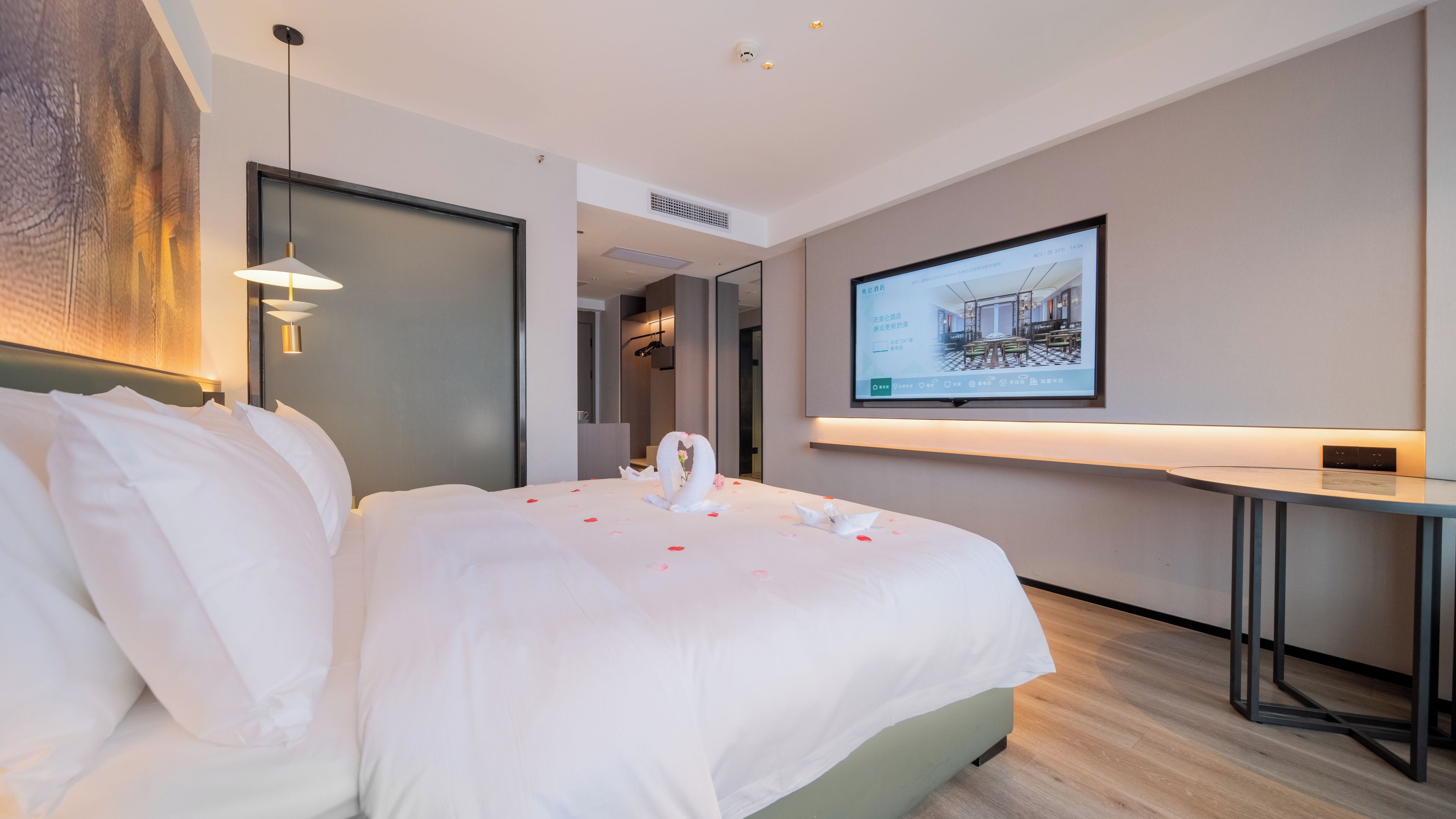 Une chambre d’hôtel avec un grand lit, un bureau et un téléviseur fixé au mur.