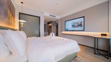 Una habitación de hotel con una cama grande, un escritorio y un televisor montado en la pared.