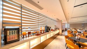 Eine moderne Hotellobby mit einer langen Rezeption, einer Sitzgelegenheit und einem großen Fenster mit horizontalen Rollläden.