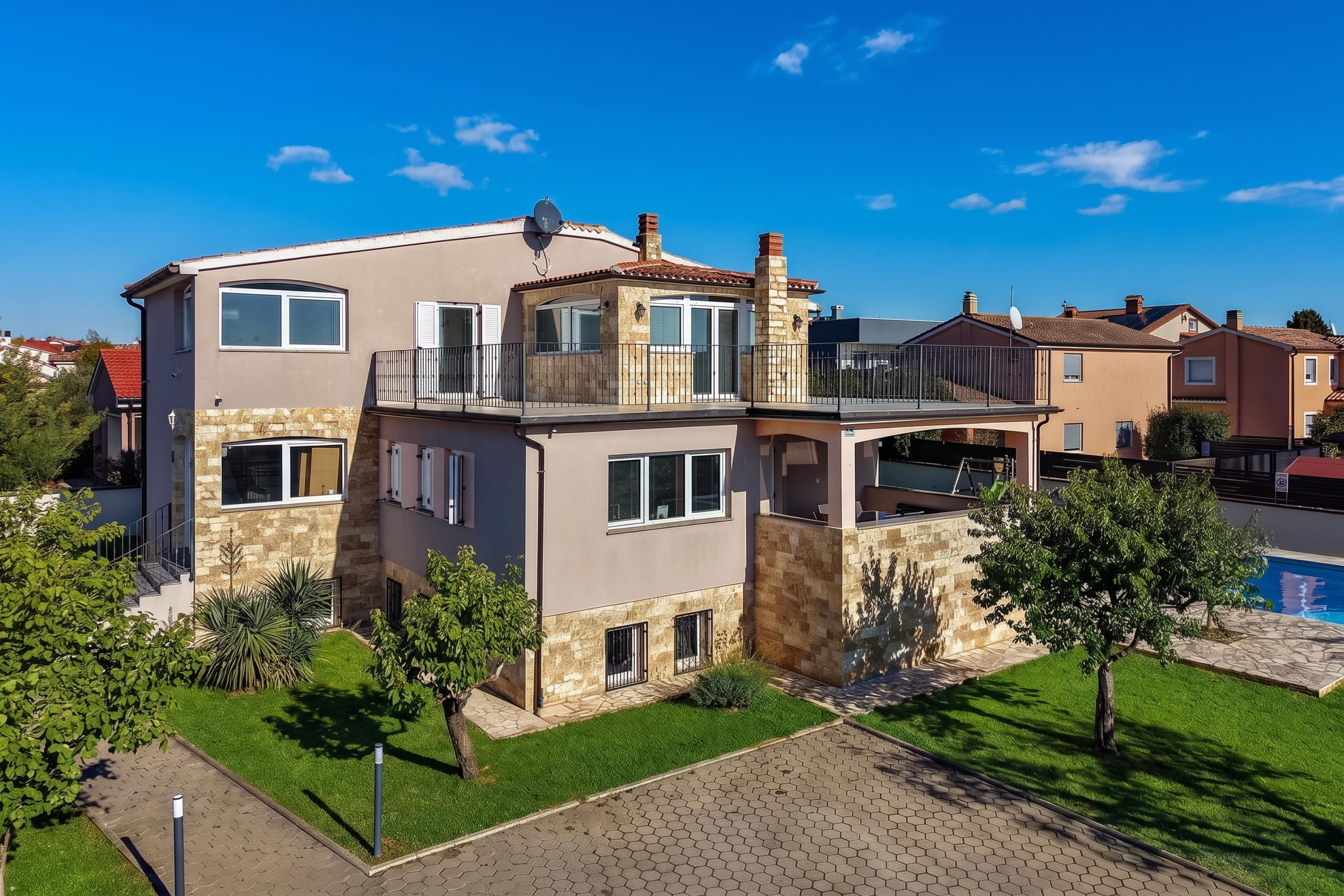 Une maison à deux étages dotée d’un balcon, d’une piscine et d’une pelouse bien entretenue.