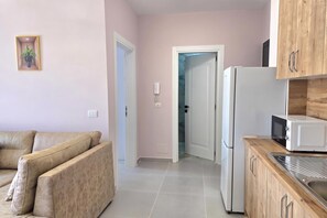 Eine moderne Küche mit Kühlschrank, Mikrowelle und Holzschränken. Im Wohnbereich befindet sich ein beiges Sofa.