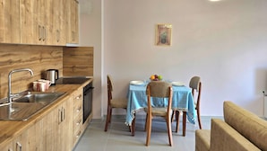 Una cocina compacta con armarios de madera, un fregadero y una zona de comedor con una mesa dispuesta para dos personas.