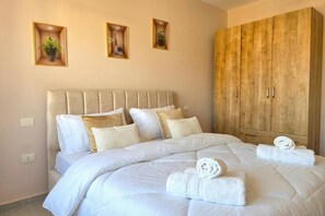 Ein Schlafzimmer mit einem Bett, Kissen, einem Holzschrank und drei Wandregalen mit Pflanzen.