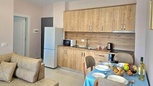 A modern kitchen with wooden cabinets, a dining table set with plates, glasses, and a bottle of wine. - Happy Stay Apartment by the Sea 095, Durres, Albania (Durres)