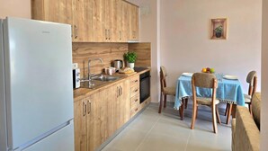 A kitchen with wooden cabinets, a stainless steel refrigerator, a sink, a stove, and a dining table with chairs. - Happy Stay Apartment by the Sea 095, Durres, Albania (Durres)