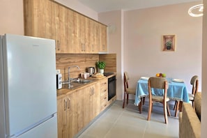 Eine Küche mit Holzschränken, einem Edelstahlkühlschrank, einem Spülbecken, einem Herd und einem Esstisch mit Stühlen.