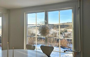 A room with a large window, a table, and two chairs.