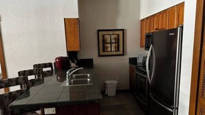 A kitchen with a granite countertop, stainless steel appliances, wooden cabinets, and a framed picture on the wall. - 2-bedroom Hyatt Main Street Station - Peak 9 in Breckenridge with Mountain View (Breckenridge)