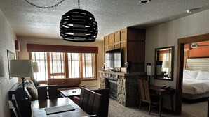 A hotel room with a dining area, a fireplace, a TV, and a bed. - 2-bedroom Hyatt Main Street Station - Peak 9 in Breckenridge with Mountain View (Breckenridge)