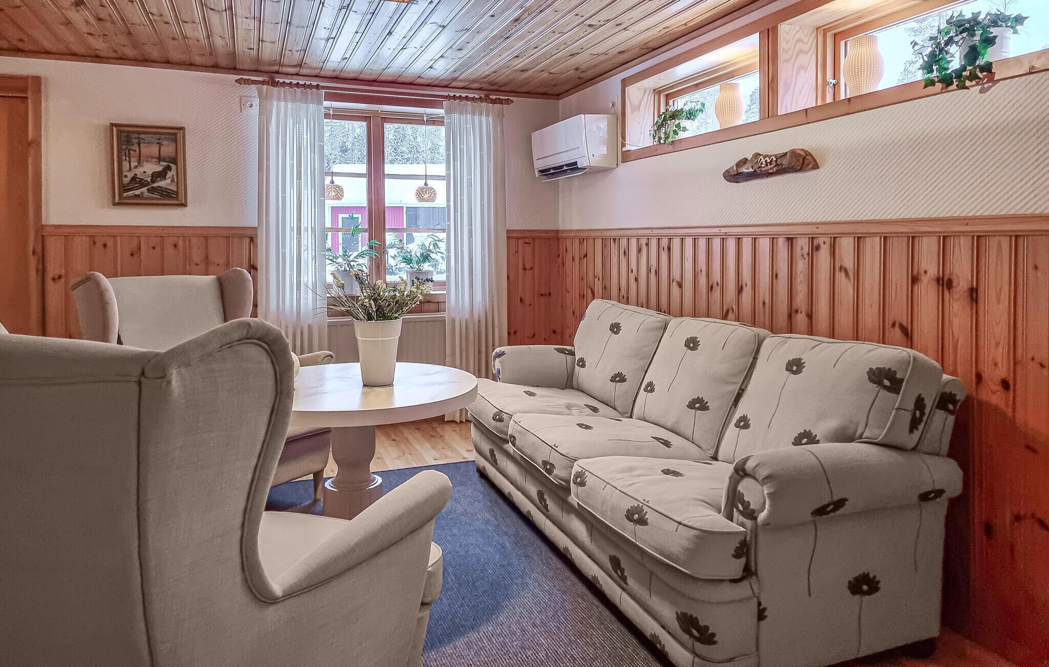 A cozy room with a wooden ceiling, a sofa, a table, and a chair.