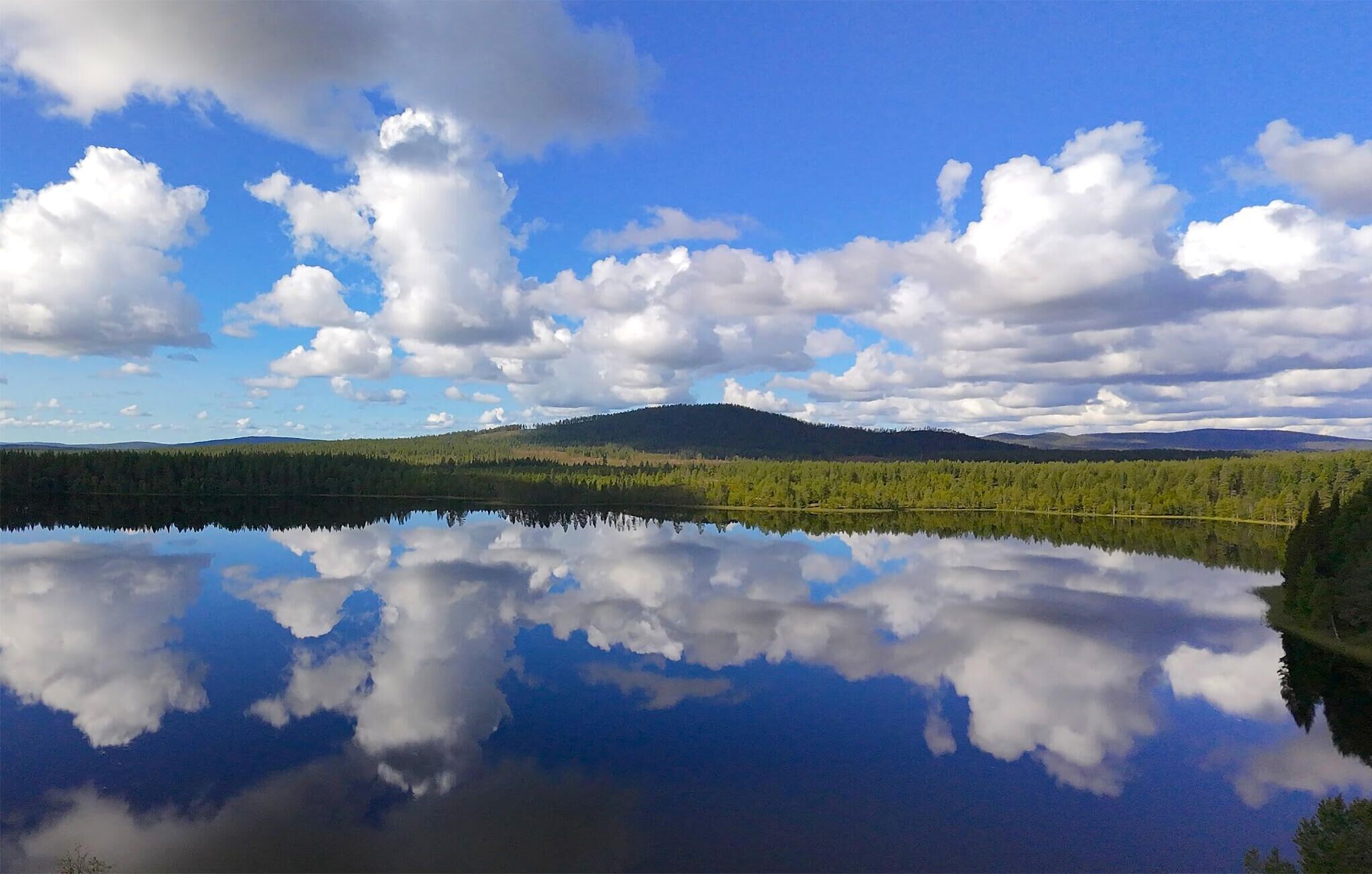 Un lac paisible qui reflète le ciel et la forêt environnante.