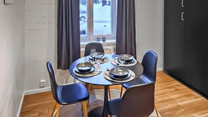 Un coin repas avec une table ronde dressée pour quatre personnes, entourée de chaises bleues aux pieds en bois.