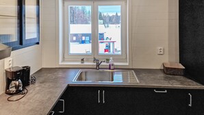 A kitchen with a large window, a stainless steel sink, and a coffee maker.