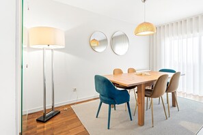 A dining area with a wooden table, blue and brown chairs, a floor lamp, and two wall-mounted mirrors. - GuestReady - Panoramic Ocean View Duplex (Lavra)
