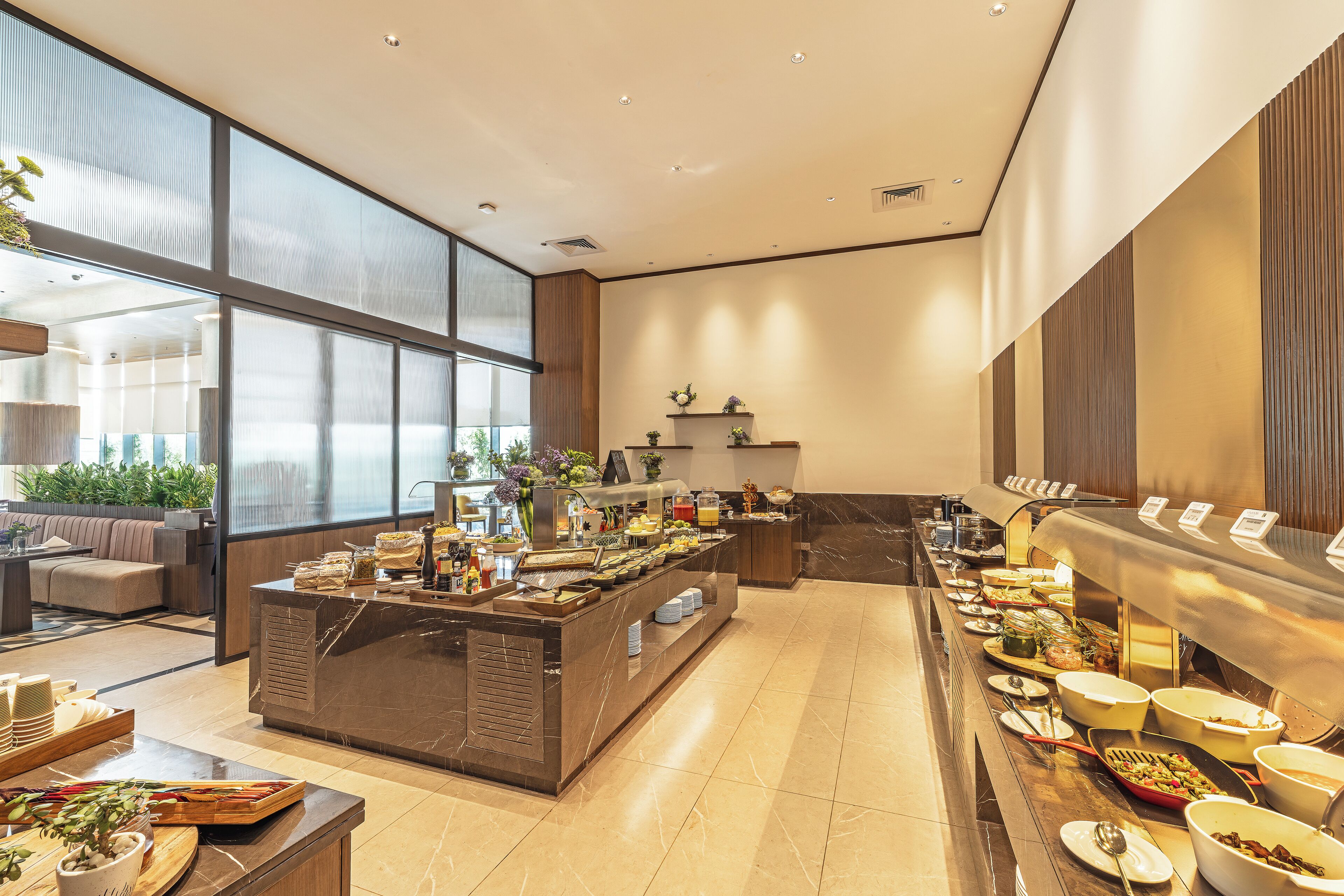 A hotel lobby with a buffet, seating area, and large windows.