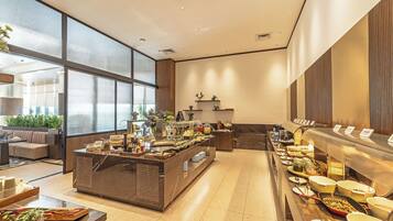A hotel lobby with a buffet, seating area, and large windows.