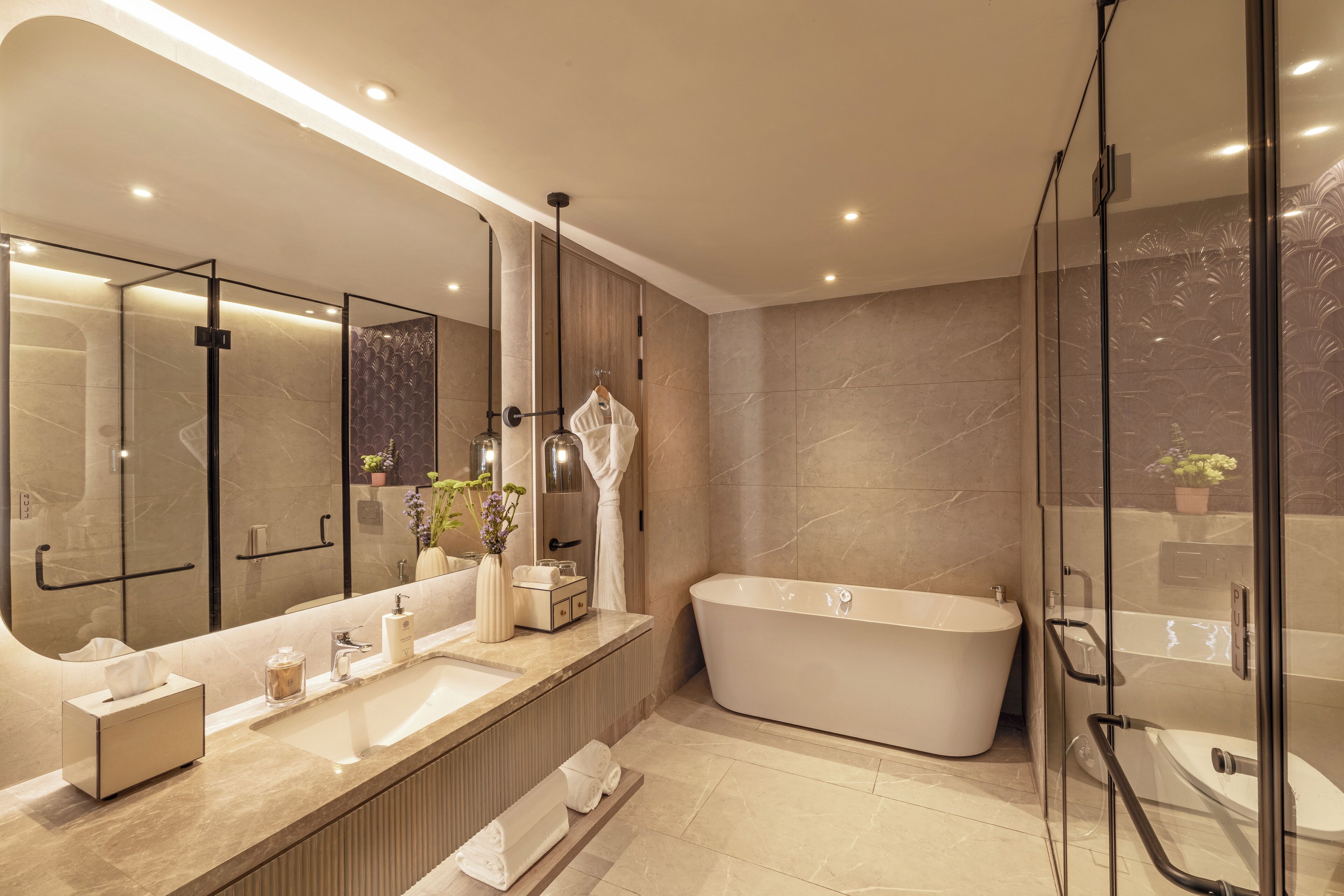 A modern bathroom with a large mirror, a freestanding bathtub, and a glass-enclosed shower area.