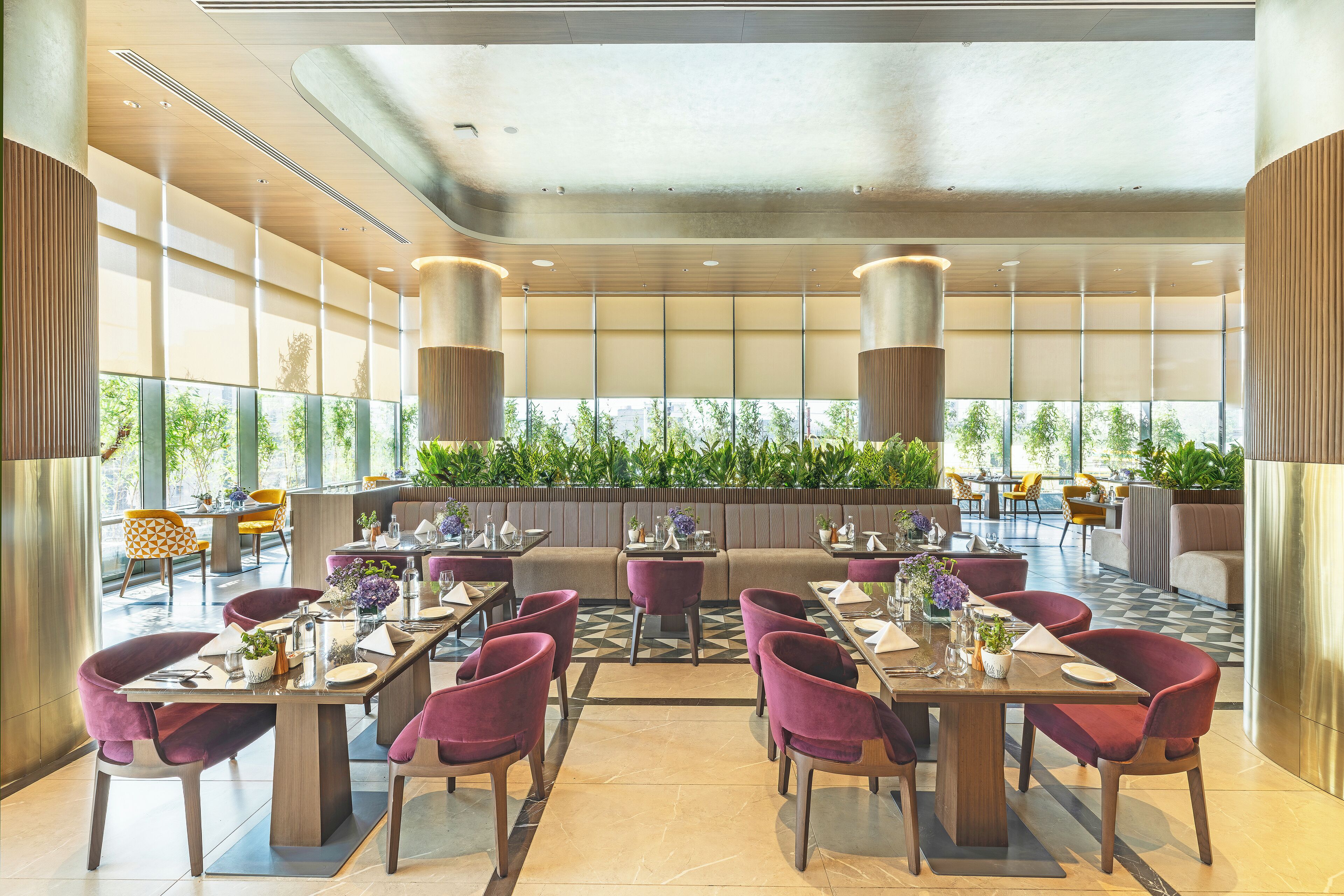 A modern restaurant with high ceilings, large windows, and a variety of seating arrangements including tables and booths.