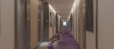 Un pasillo de hotel con una alfombra larga, puertas y cuadros en las paredes.