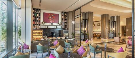 A modern hotel lobby with seating areas, a kitchen, and a large window.