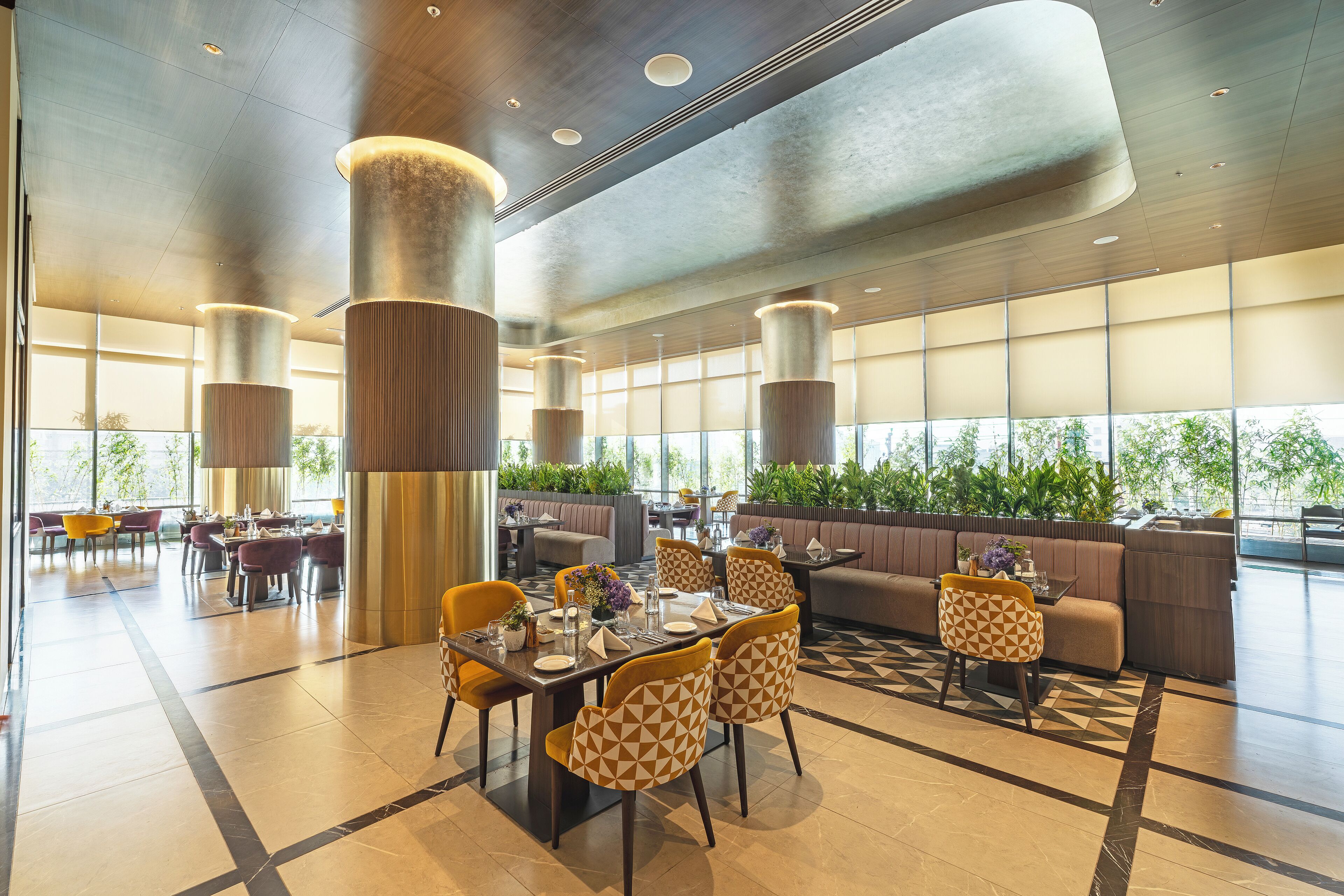 A spacious indoor area with multiple seating arrangements, including tables and chairs, and a large window providing natural light.