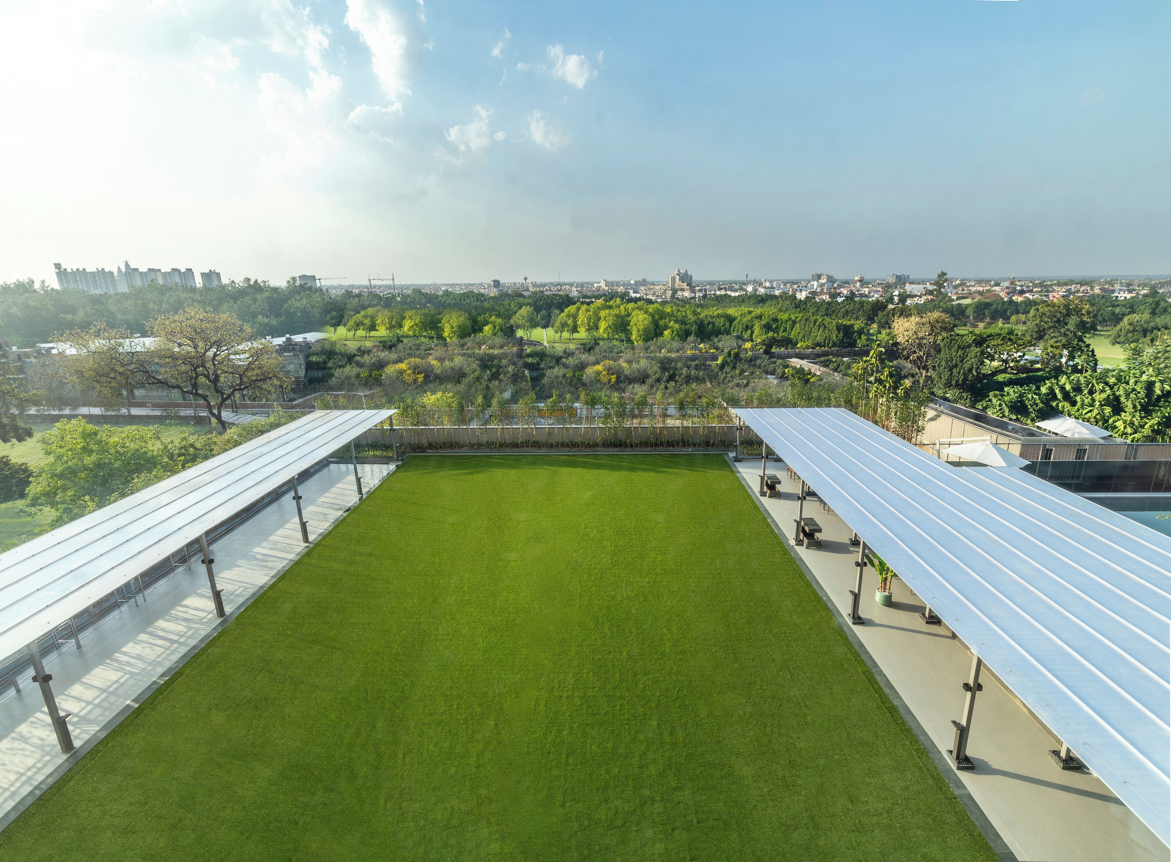 A rooftop with a green lawn, solar panels, and a view of a cityscape.