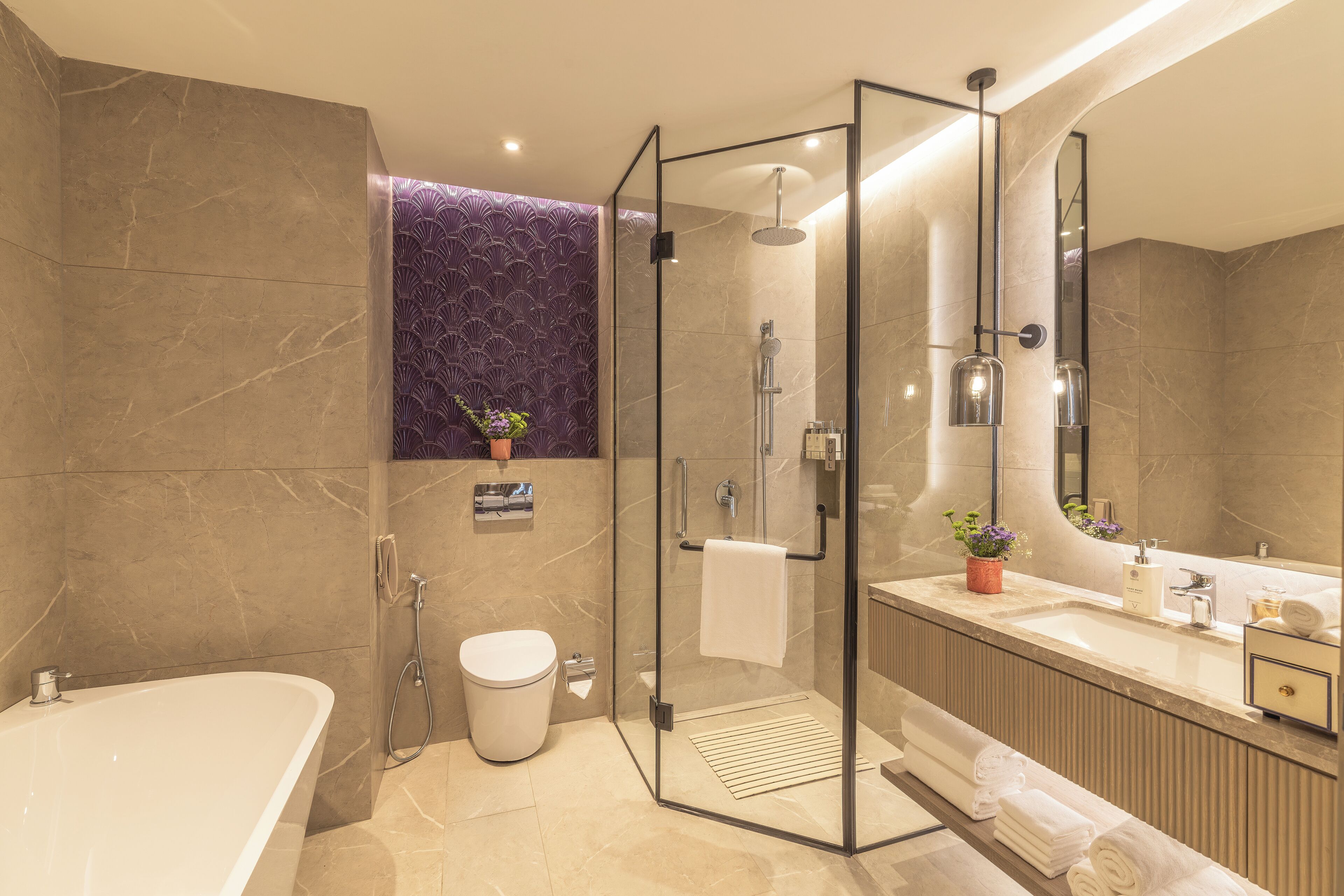 A modern bathroom with a glass-enclosed shower, a freestanding bathtub, and a vanity with a mirror.