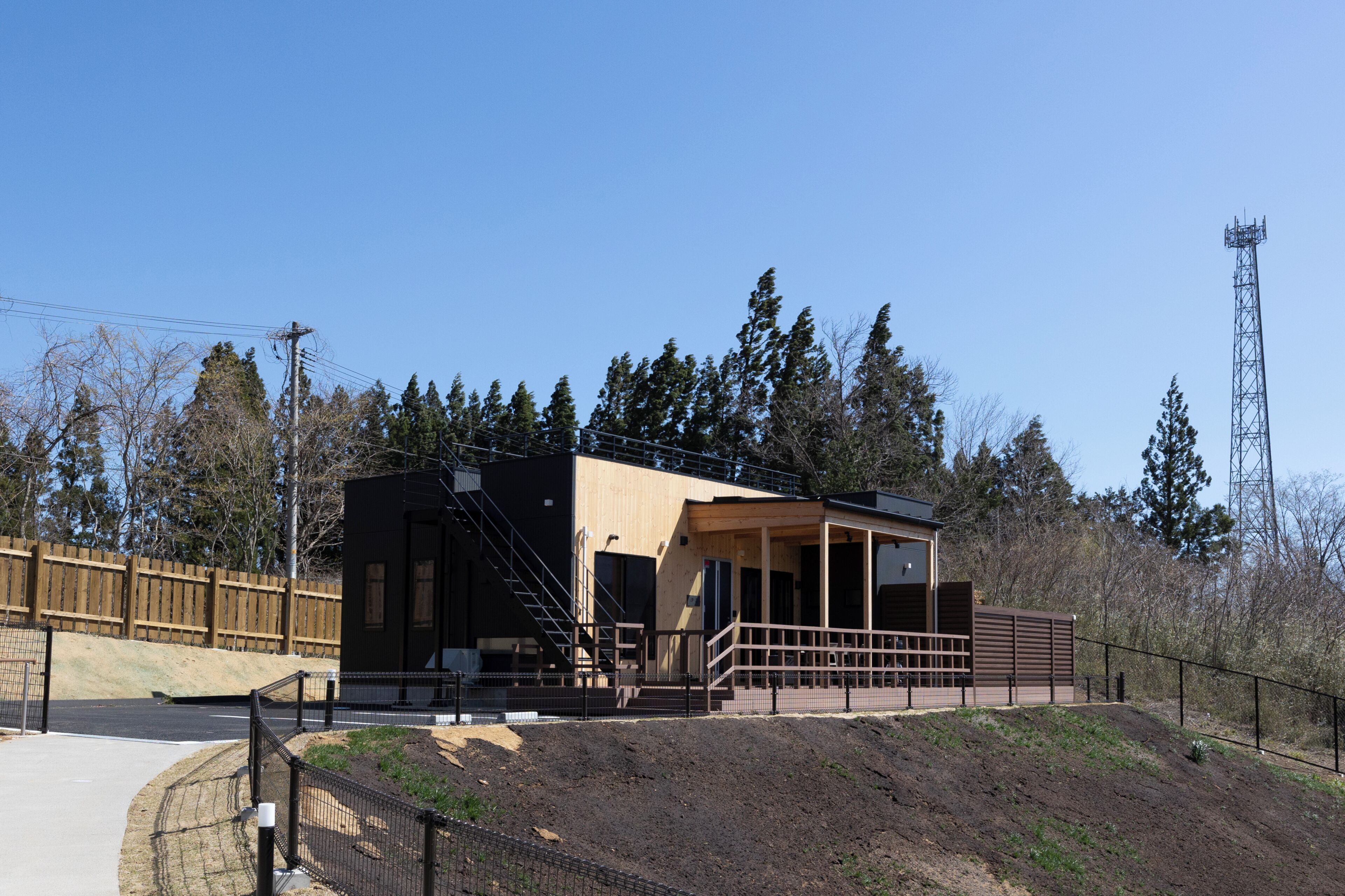 A building with a wooden exterior, a covered outdoor area, and a fenced perimeter.