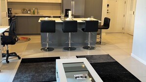 Uma cozinha moderna com ilha central, banquetas de bar e área de jantar com mesa e cadeiras.